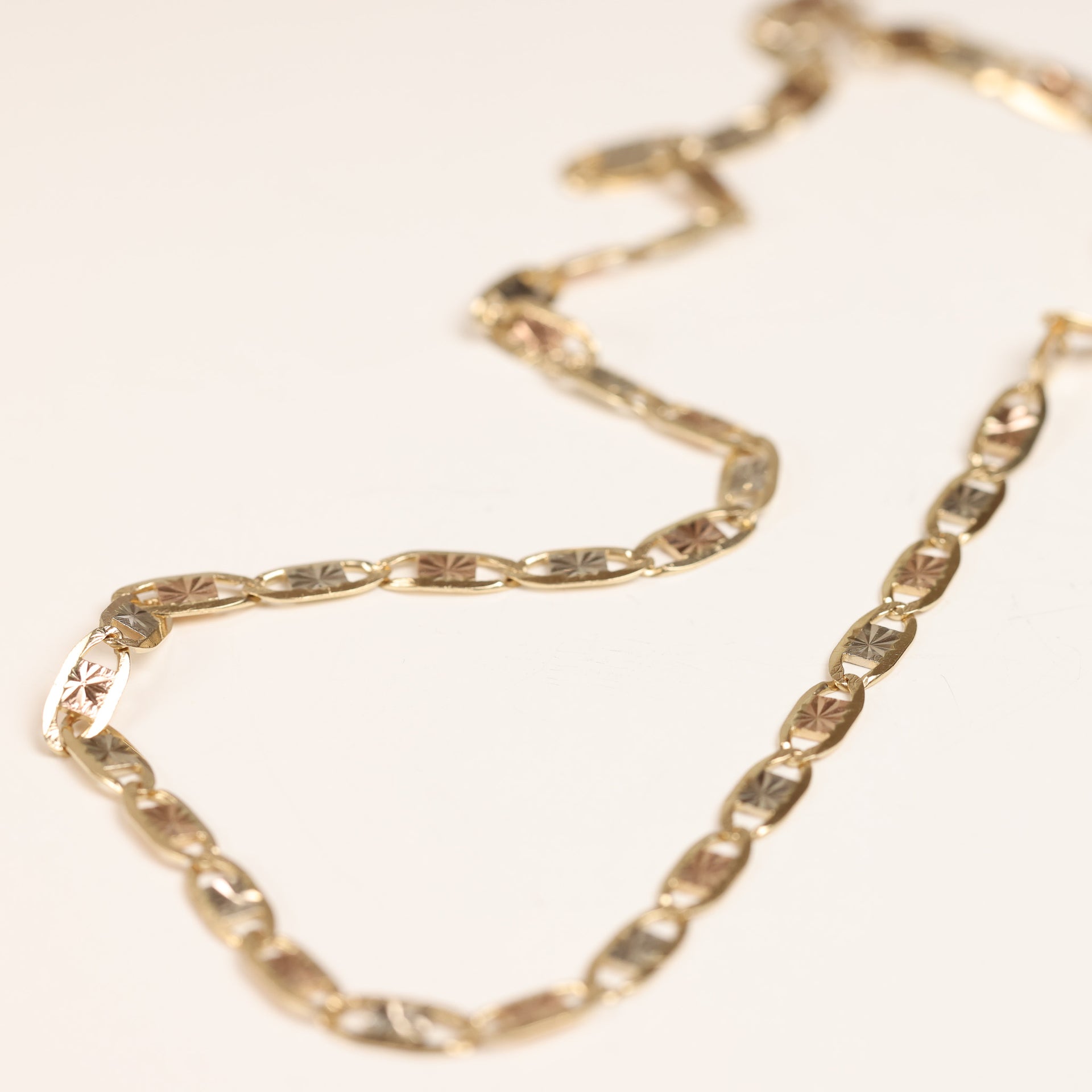 A gold chain necklace with oval-shaped, embossed links is shown against a plain white background, elegantly complementing the 14 Karat Yellow Gold Tanzanite Diamond Ring - Size 5.
